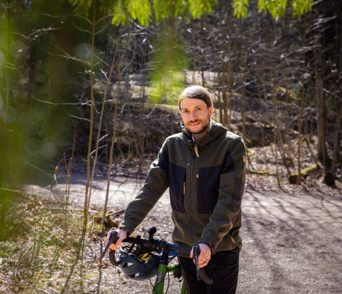 Jussi-Pekka Teini taluttaa pyöräänsä metsätiellä.