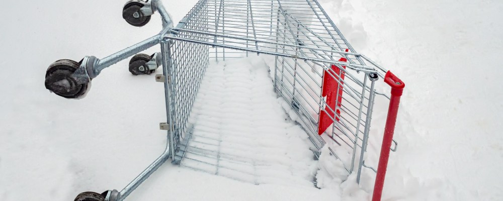 Ostoskärry makaa kyljellään lumessa.