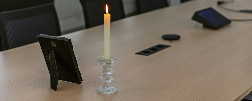 Kynttilä ja kehyksissä oleva kuva tyhjässä kokoushuoneessa.