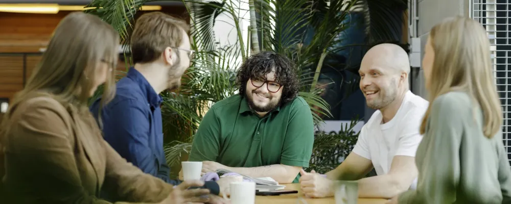 kumpulan kampuksella henkilöitä pöydän äärellä