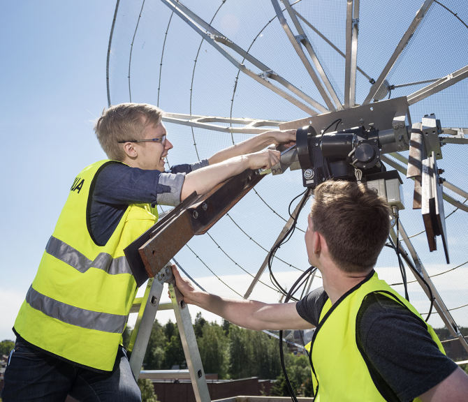 Kaksi henkilöä korjaa satelliittiantennia