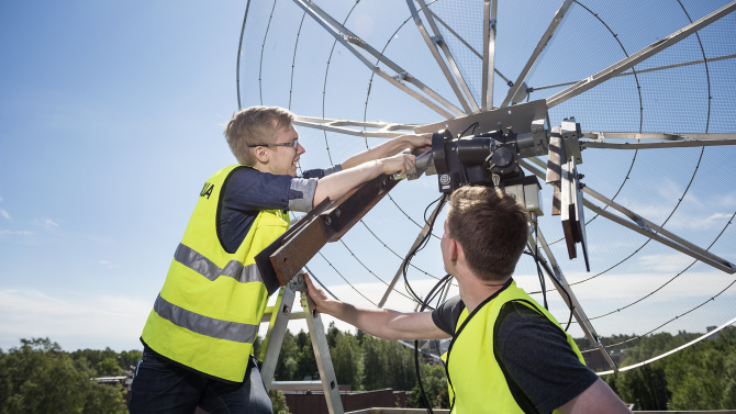Kaksi henkilöä korjaa satelliittiantennia