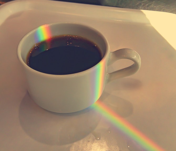 kahvikuppi, johon heijastuu sateenkaari