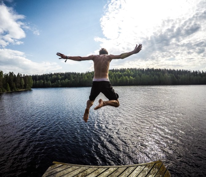 Henkilö hyppäämässä kesäiseen järveen