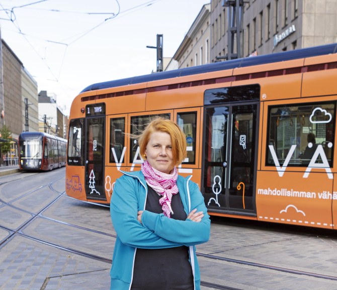Sanna Nokelainen seisoo kadunkulmassa Tampereella, takanaan ratikoita.