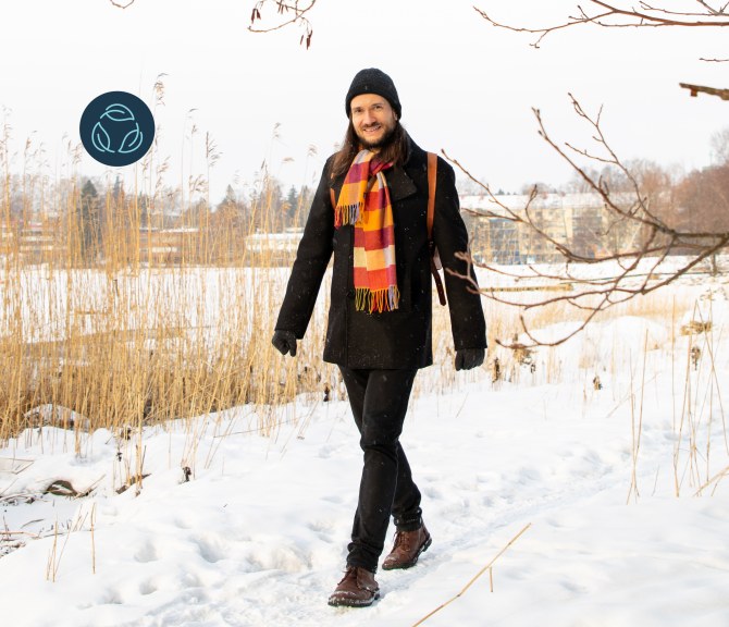 Jussi-Pekka Teini kävelee lumista polkua kaislikon ohi.