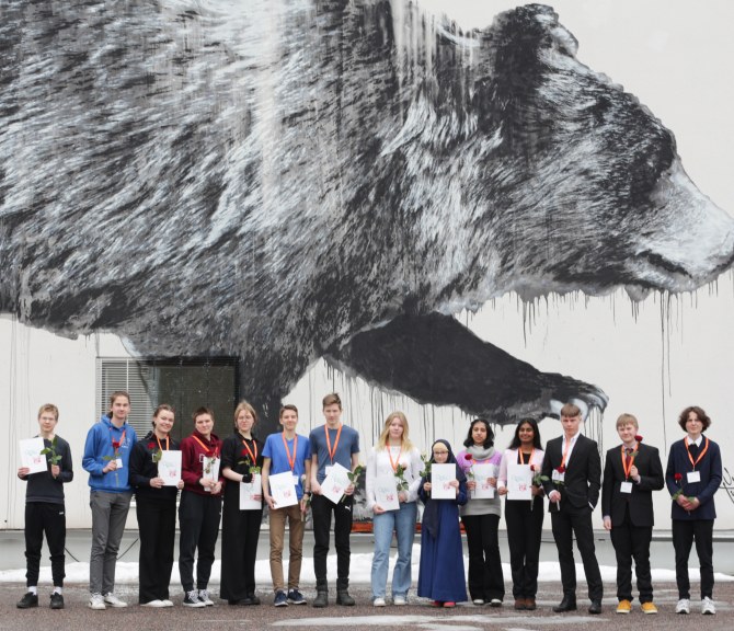 Winners of the TuKoKe 2023 Competition, behind them a wall painting of a bear.
