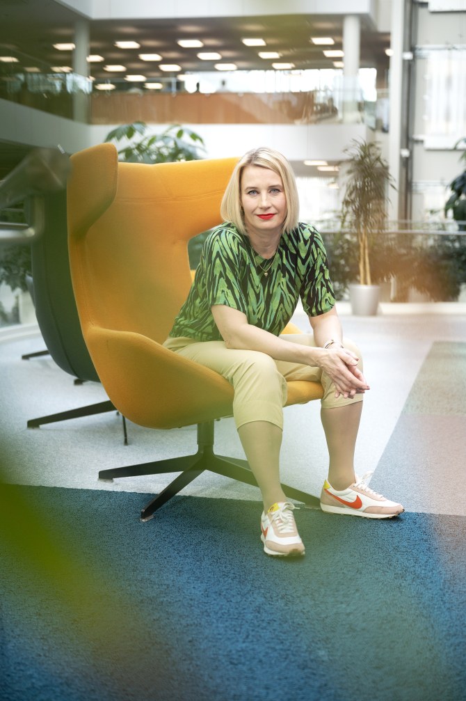 Pia Kautonen istuu oranssilla nojatuolilla valoisassa ja avarassa sisätilassa.