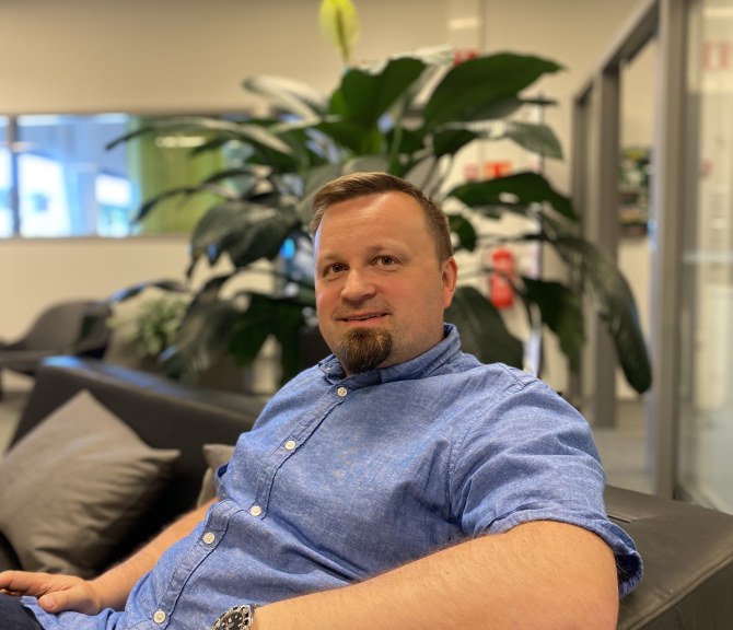 Timo Välikangas istuu mustalla sohvalla toimistotilassa.