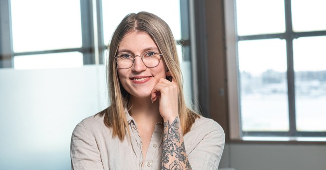 Karoliina Oksanen seisoo valoisassa tilassa ikkunan äärellä.