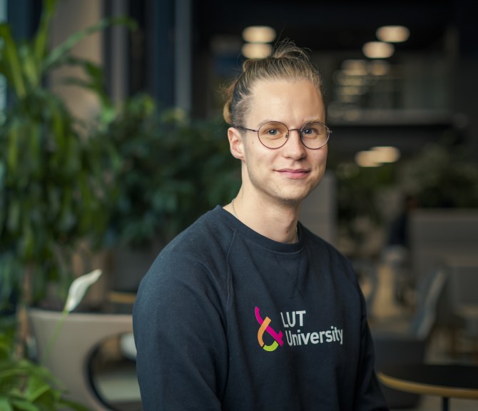 Niilo Hendolin yllään LUT-yliopiston paita, taustalla huonekasveja.