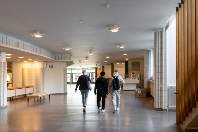 Kolme opiskelijaa kävelee Aalto-yliopiston kandidaattikeskuksen käytävällä