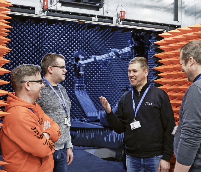 Harri Kaarre (vasemmalla), Mika Mäntymäki, Marko Honkalampi ja Marko Määttä juttelevat viikonlopun ylitöistä CATR-kammion (Compact Antenna Test Range) edessä. Oranssit piikit ovat absorbereita, jotka vaimentavat signaalit.