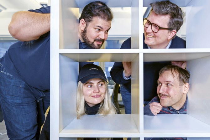 Unicuksen toimitusjohtaja ja kolme työntekijää kurkistaa hyllykön takaa.