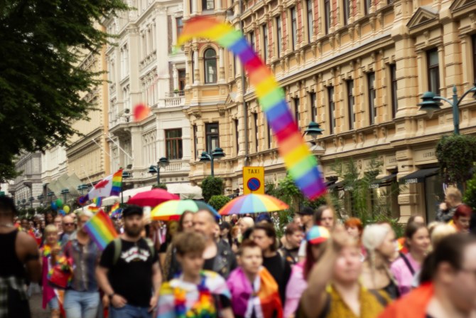Helsinki Pride -kulkue kulkemassa kantakaupungissa. Taustalla näkyy rakennuksia ja etualalla kulkueen osallistujia. 
