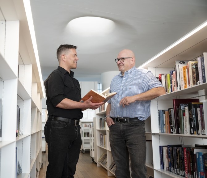 Mikko Hyökki ja Risto Kauppinen juttelevat Oodin kirjahyllyjen välissä.