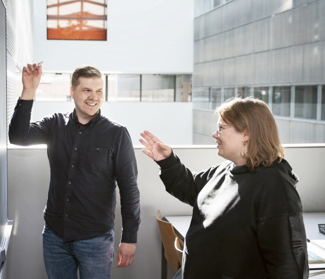 Topi Törmä ja Anne-Maria Ernvall-Hytönen juttelevat liitutaulun äärellä.