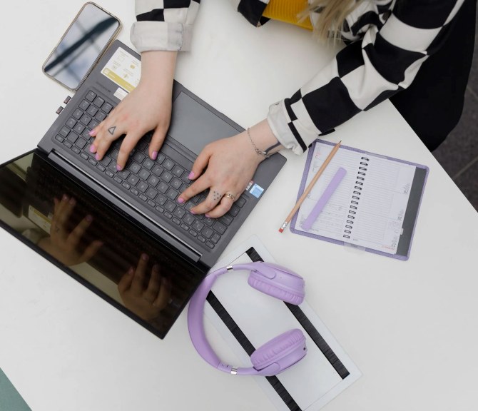 Ylhäältä päin otettu kuva henkilöstä, joka käyttää kannettavaa tietokonetta.