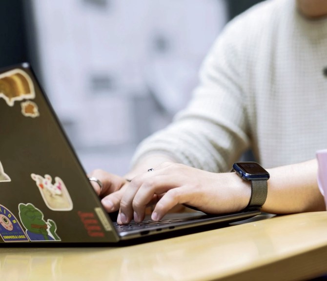 Lähikuvassa nuoren ihmisen kädet kirjoittamassa tietokoneella.