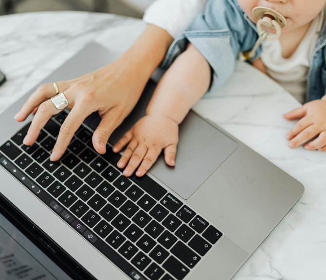 Aikuinen ja vauva yhdessä kannettavan tietokoneen äärellä