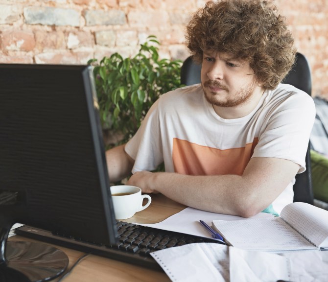 Mies istuu tietokoneen ääressä.