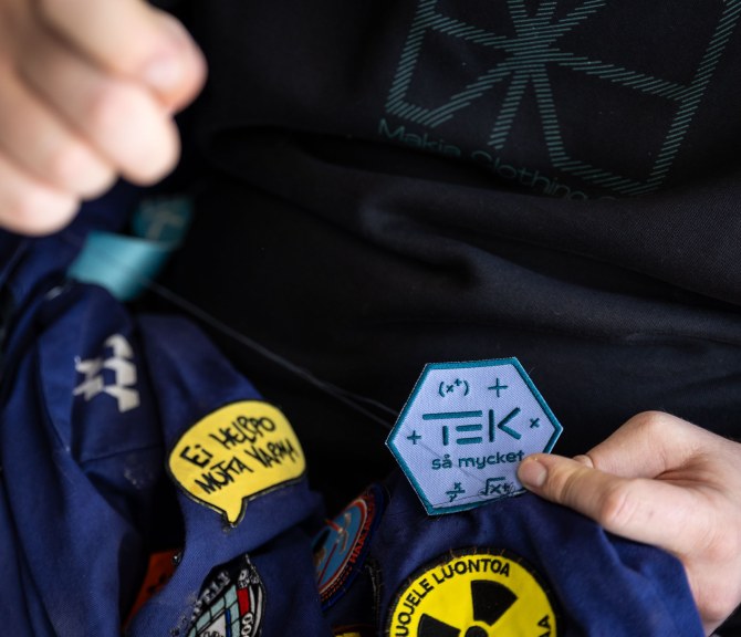 Lähikuvassa merkin ompelua haalareihin.