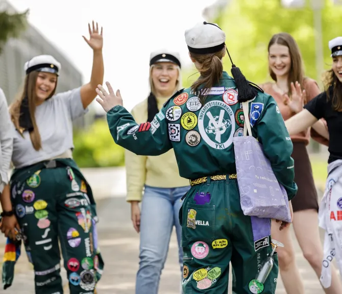 Joukko opiskelijoita tervehtii iloisesti toisiaan.