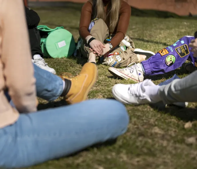 Opiskelijoita istumassa nurmikolla.