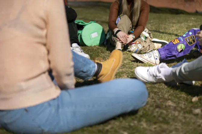 Opiskelijoita istumassa nurmikolla.
