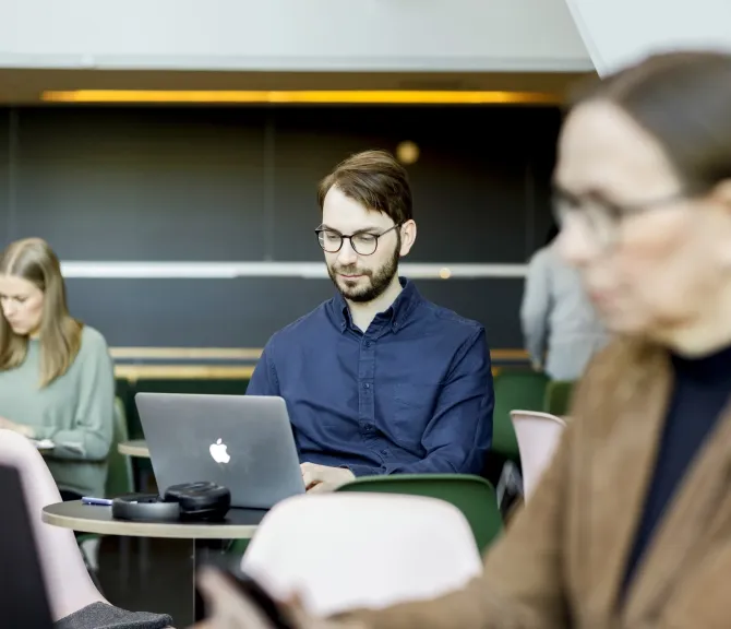 Kolme henkilöä keskittyy omaan tekemiseensä, kuten tietokoneella työskentelyyn.