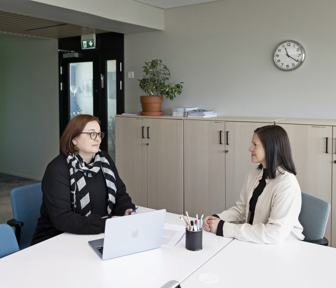Sari Haataja-Helander ja Katja Sulenko istuvat pöydän ääressä ja keskustelevat.
