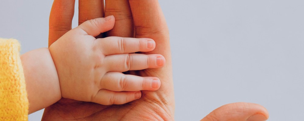 Two hands: one is an adult hand and the other a hand of a baby.