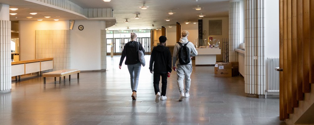 Kolme opiskelijaa kävelee Aalto-yliopiston kandidaattikeskuksen käytävällä