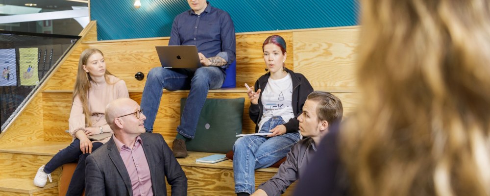 Henkilöitä istuu TEK Loungen katsomossa Tampereella.