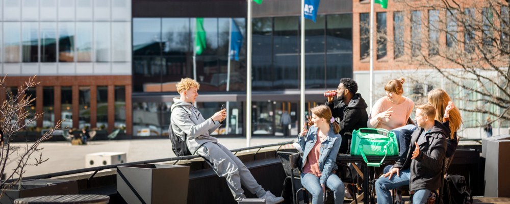 Opiskelija ottaa kuvaa kaveriporukastaan terassilla Aalto-yliopistolla