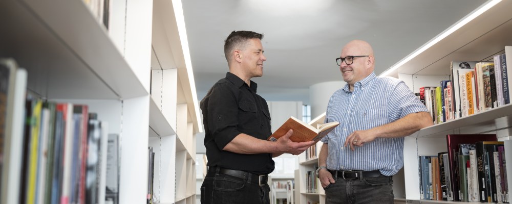 Mikko Hyökki ja Risto Kauppinen juttelevat Oodin kirjahyllyjen välissä.