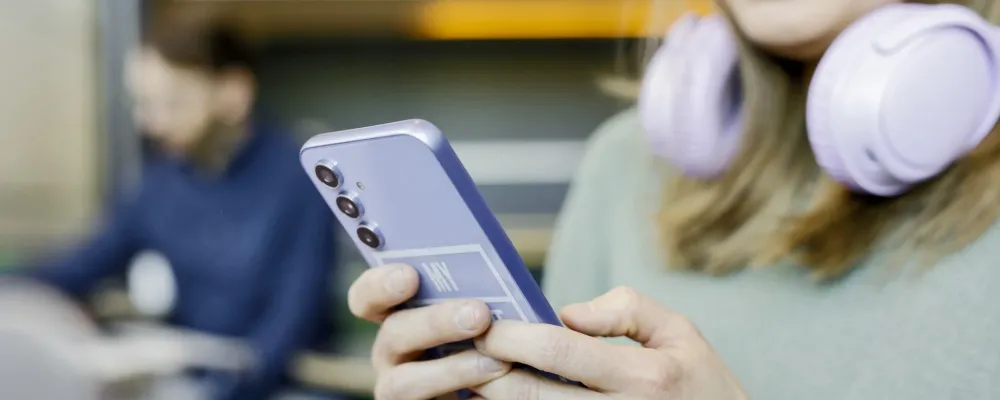 Lähikuvassa henkilö lukee puhelimeltaan jotain.