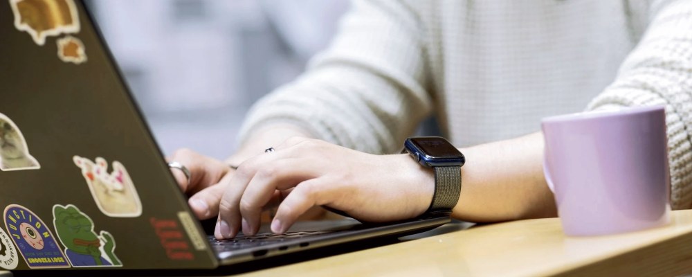 Lähikuvassa nuoren ihmisen kädet kirjoittamassa tietokoneella.