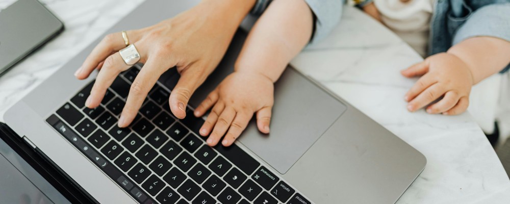 Aikuinen ja vauva yhdessä kannettavan tietokoneen äärellä