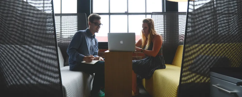 Kaksi henkilöä ideoi ja suunnittelee tietokoneen äärellä.
