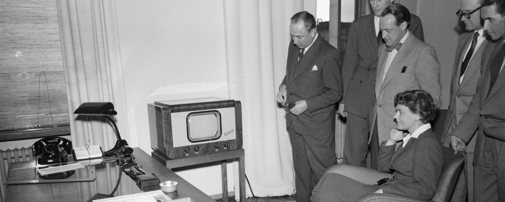 Mustavalkoinen kuva televisiosta ja ihmisistä katsomassa sitä.