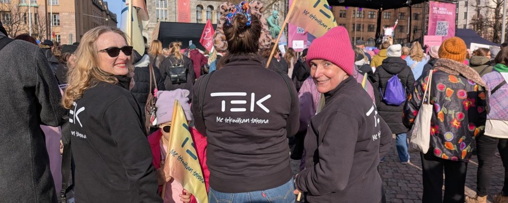 TEKin edustajat seisovat Rautatientorilla, jossa on paljon ihmisiä.