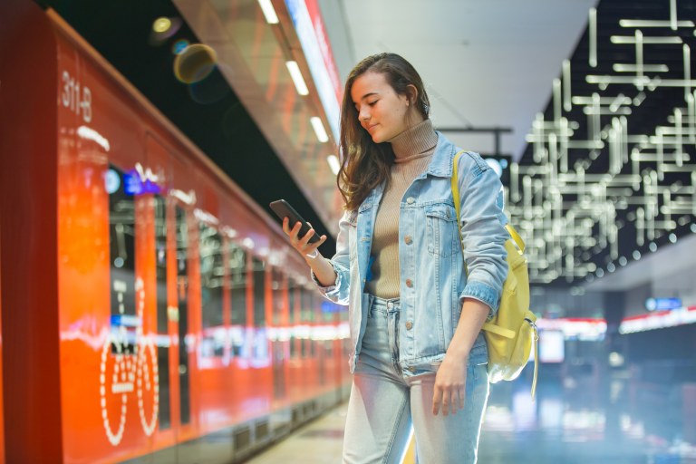 Henkilö metroasemalla kirjoittamassa puhelimella