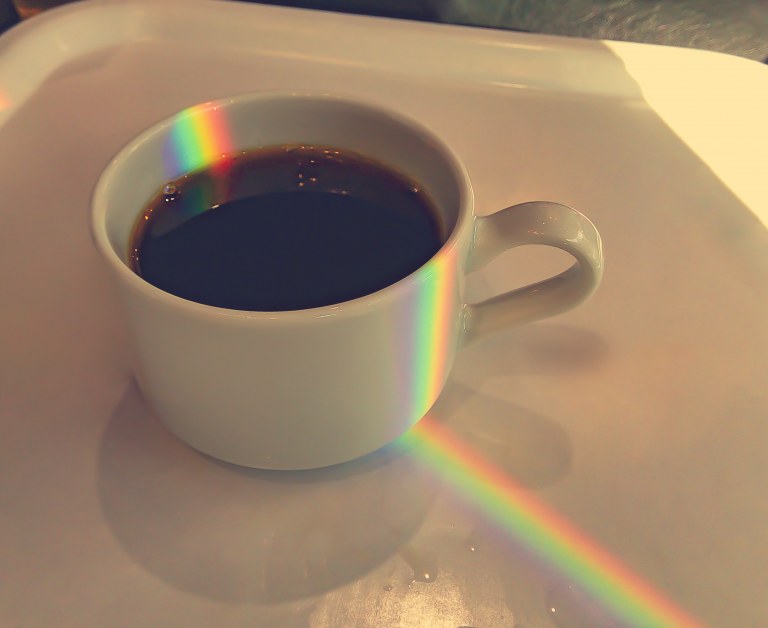 kahvikuppi, johon heijastuu sateenkaari