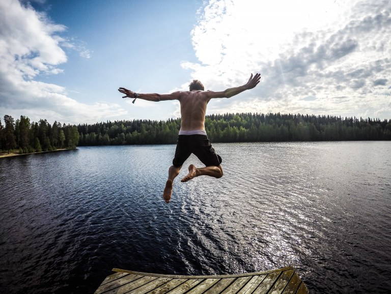 Henkilö hyppäämässä kesäiseen järveen