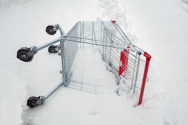 Ostoskärry makaa kyljellään lumessa.
