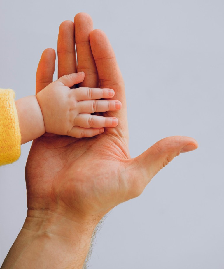 Two hands: one is an adult hand and the other a hand of a baby.
