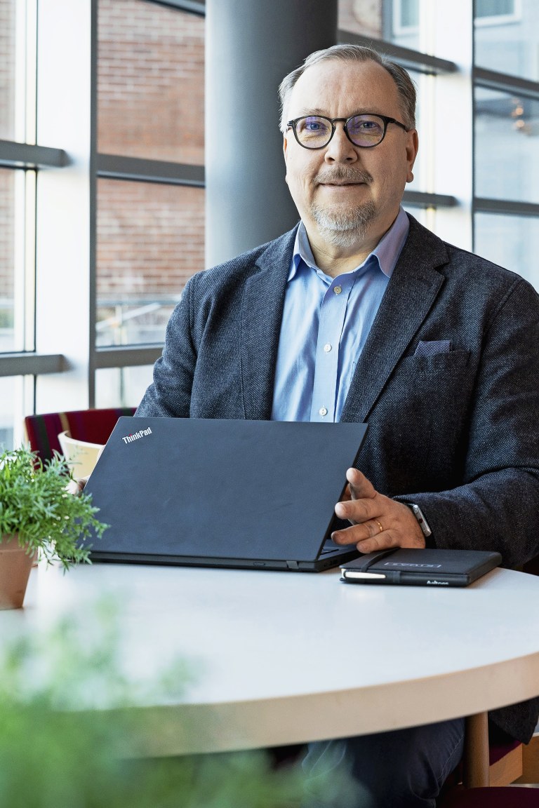 Petri Jehkonen istuu kannettavan tietokoneen ääressä, takanaan suuri ikkuna.