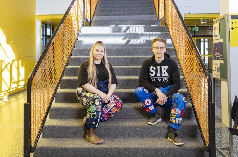 Veera Kiiskilä ja Anders Nikula istuvat portaikossa yllään opiskelijahaalarit.