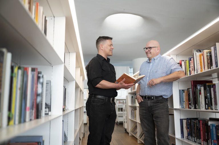 Mikko Hyökki ja Risto Kauppinen juttelevat Oodin kirjahyllyjen välissä.